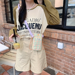 Detail of a colorful plaid crossbody bag paired with a khaki raglan sleeve letter t-shirt