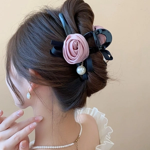 Detail view of pink rose and bow hair claw clip with pearl on a half-up hairstyle