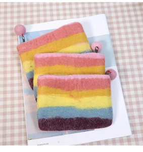 Rainbow striped handmade wool felt coin purses stacked on a magazine background