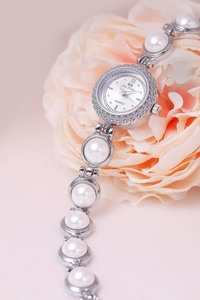 Detail of luxury pearl bracelet watch with silver case and crystal bezel for women