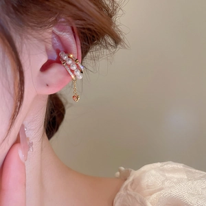 Detail of gold-plated triple layer ear cuff with pearls, zircon, and a heart tassel