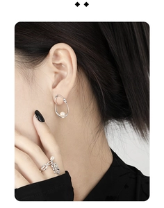 Detail showing elegant silver oval hollow pearl earrings and ring on a model