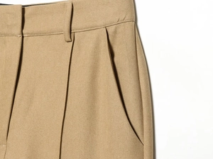 Detail of khaki twill trousers showing waist pleats, belt loops, and side pockets