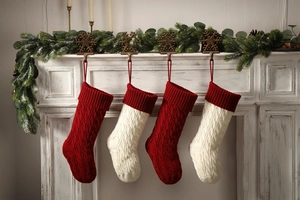 Detail of four red and white knitted Christmas stockings with chunky cable patterns