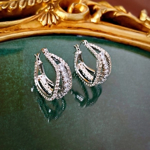Macro detail of double-layer geometric hoop earrings with cubic zirconia in silver finish
