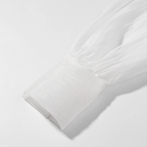 Detail of white pleated chiffon sleeve with elastic cuff and textured fabric