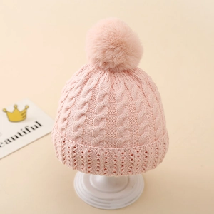Detailed knit cable pattern and faux fur pom-pom on warm pink newborn winter beanie