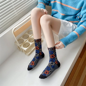 Detail of floral vintage socks with blue and orange flowers on dark grey cotton fabric