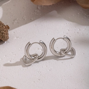 Detailed view of silver stainless steel heart hoop earrings on a natural background