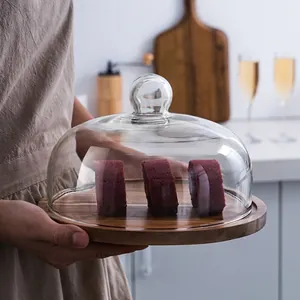Wooden cake stand with clear glass dome lid showcasing red velvet dessert rolls