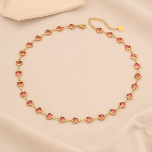 Elegant gold necklace with pink heart gemstones on soft beige fabric background