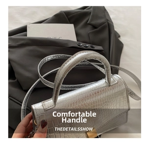 Close-up of silver crocodile pattern texture with metallic clasp on a stylish square bag