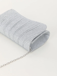 Detailed macro view of silver glitter fabric texture and pleated folds on evening clutch