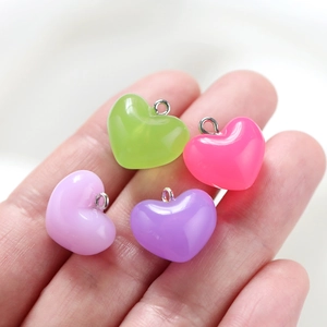 Handheld view of four colorful jelly acrylic heart pendants with silver metal rings