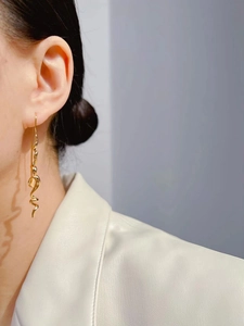 Close-up of long gold spiral earrings on model, showcasing minimalist irregular lines