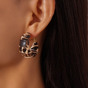 Detail of leopard print leather wrapped C-shaped earrings with golden hoop on model