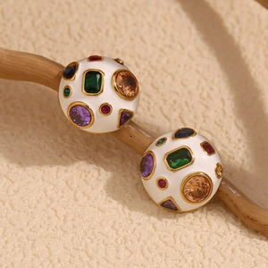 Detail of white enamel dome earrings set with colorful zircon on a rustic wood branch