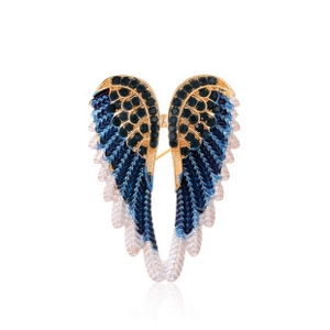 Detail of angel wing brooch with deep blue gemstones and white enamel on golden finish