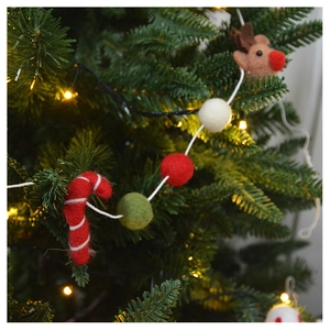 Close-up of wool felt Christmas ornaments with reindeer and candies on a festive tree