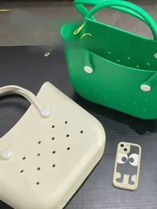 Detail of vibrant green and cream EVA beach bags with signature holes and accessory