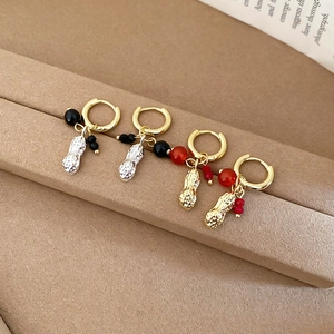 Detailed view of beaded peanut pendant earrings in gold and silver finish on display