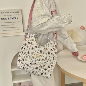 Close-up of white quilted tote bag featuring cartoon character prints and logo tag