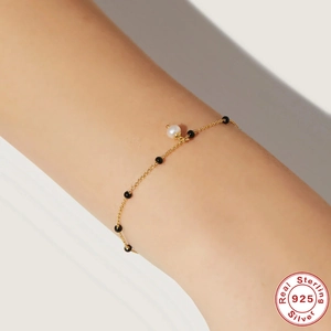 Close-up of S925 sterling silver gold bracelet with white pearl on a female wrist