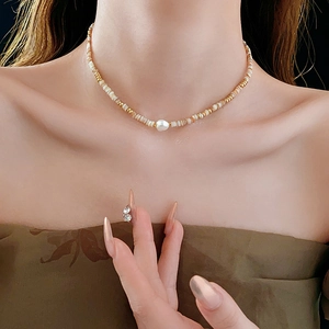 Detail of 14K gold plated beaded necklace with baroque pearl on female neck