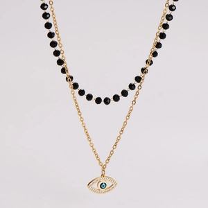 Detail of layered gold chain and black bead necklace with evil eye crystal pendant