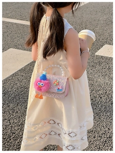 Detail of pink sequin girl's bag with pearl handle and plush doll decoration