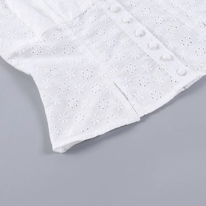 Détail du haut caraco en dentelle jacquard blanche avec broderie anglaise et boutons