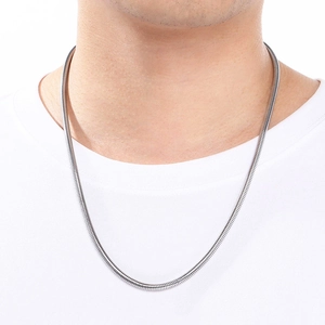 Close-up of a silver stainless steel snake bone chain necklace worn on a white t-shirt