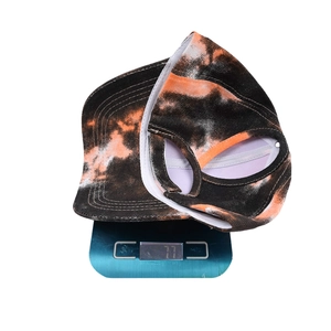 Tie-dye ponytail baseball cap in black and orange on a scale weighing 77 grams