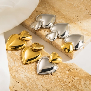 Detail of heart-shaped stud earrings in gold and silver finish on natural stone