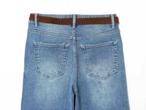Detail view of high-waist blue denim pants with brown belt and back pocket stitching