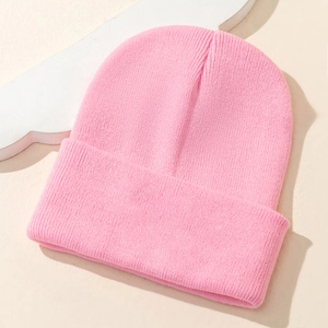 Pink knit beanie with NO BAD VIBES embroidery displayed on a neutral flat lay background