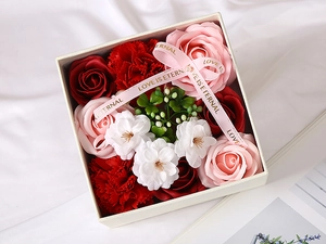 Close-up of square gift box with red roses and pink carnations with Love is Eternal ribbon