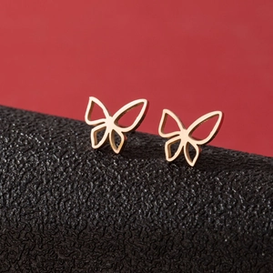 Minimalist golden butterfly stud earrings in stainless steel on a red and black background