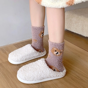 Detail of purple coral fleece socks with bear pattern and white fuzzy slippers