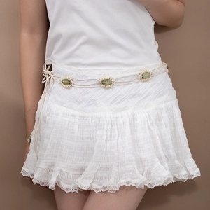 Détail de la ceinture tressée bohème avec perles sur une jupe blanche en dentelle