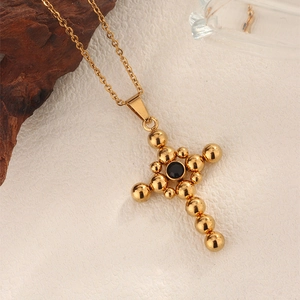Detailed macro shot of vintage gold cross pendant featuring a centered black zircon stone