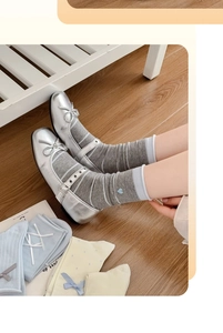 Dettaglio di calze grigie a righe con ricamo a cuore blu e scarpe argento lucido