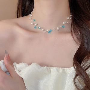 Detail of double-layer necklace with white pearls and blue crystal beads on clear wire