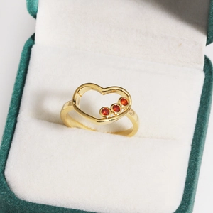 Détail de la bague coeur plaquée or 14 carats avec zircons rouges dans son écrin élégant
