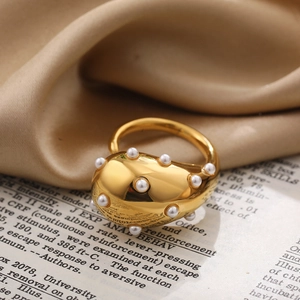 Macro detail of irregular gold ring with white pearls on vintage book and beige silk