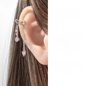 Close-up of bow knot ear cuff with pink heart gemstone and silver tassel chain