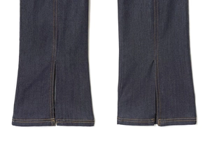 Détail d'un jean bleu foncé avec ourlet fendu à l'avant et surpiqûres orange contrastées