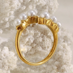 Detail of 18K gold-plated open ring with seven graduated white pearls on coral background