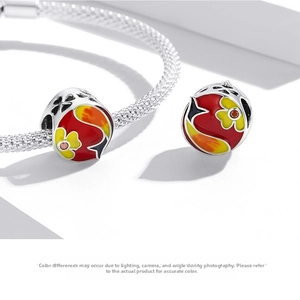 Macro detail of red enamel koi beads with silver mesh bracelet showing fine craftsmanship