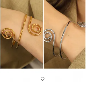 Macro detail of polished gold and silver spiral bracelets with an open adjustable design